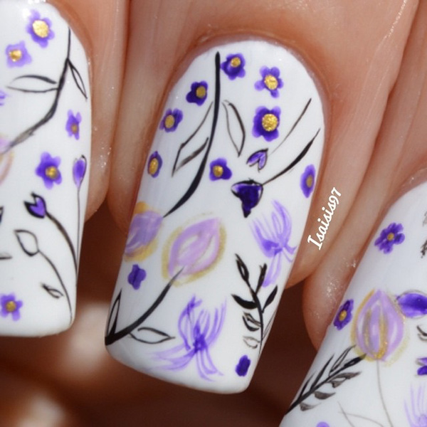 White and violet inspired spring nail art design. Coated with a white base color, simple and cute drawings of violet flowers with black outlines are painted on top giving the nails a cute and homey vibe.