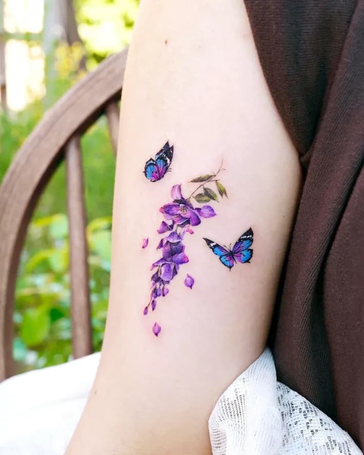 Two Butterflies flying around wisteria upper arm tattoo