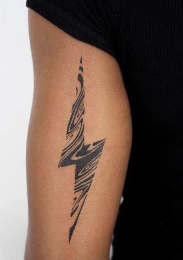 Minimalist lightning bolt tattoo on the thigh.